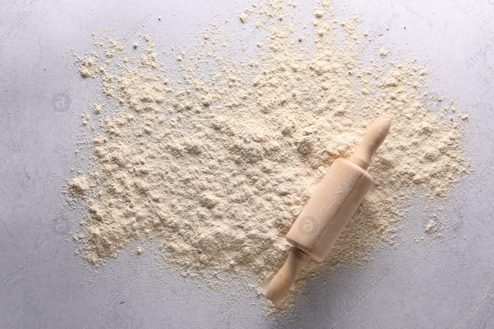 Photo of Pile of flour and rolling pin on light textured table, top view