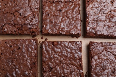 Delicious chocolate brownies on parchment paper, flat lay