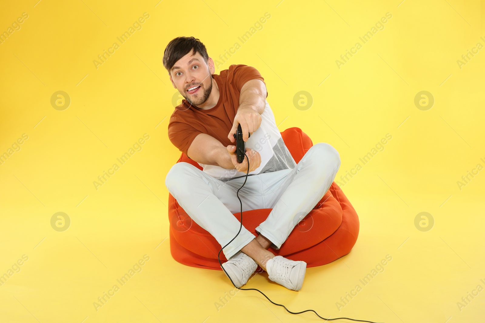 Photo of Emotional man playing video games with controller on color background