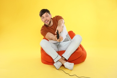 Photo of Emotional man playing video games with controller on color background