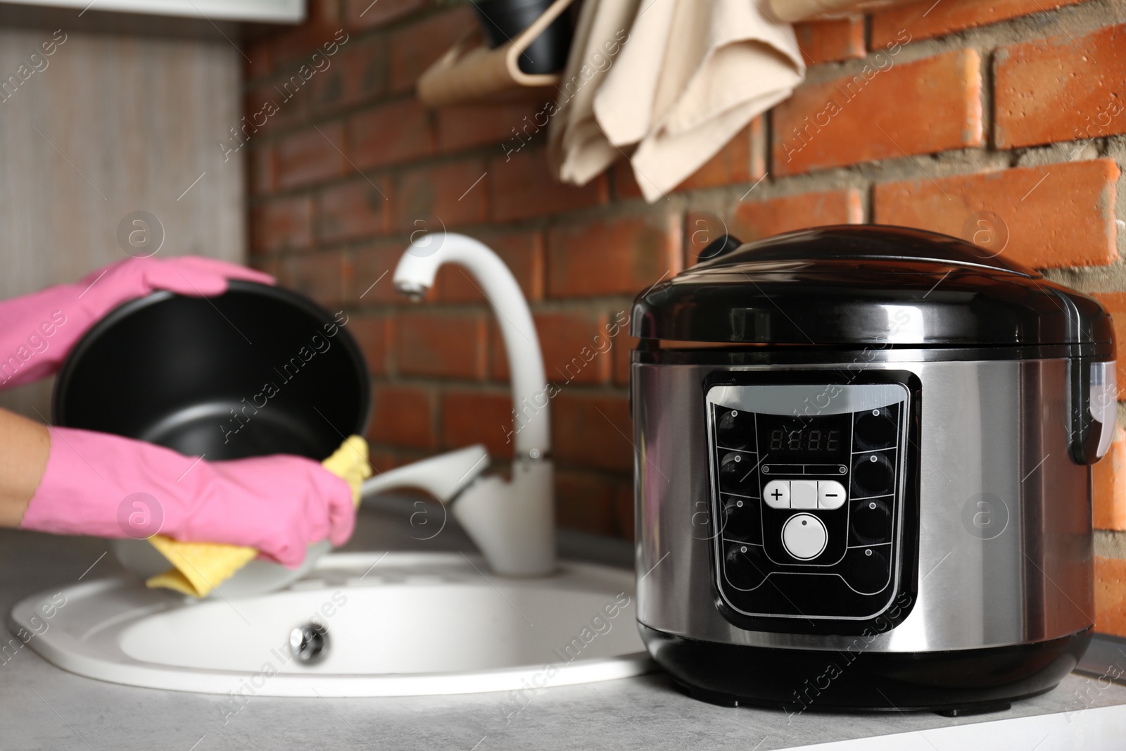 Photo of Young woman cleaning modern multi cooker in kitchen, closeup