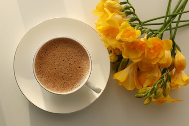Photo of Delicious morning coffee and flowers on white table, flat lay