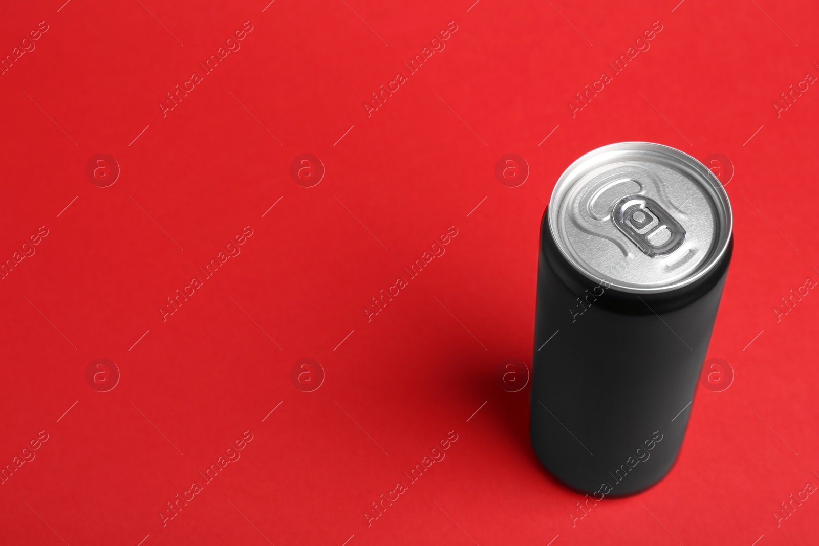 Photo of Energy drink in can on red background, space for text