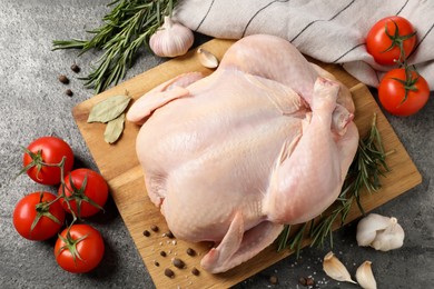 Photo of Fresh raw chicken with spices and vegetables on grey textured table, flat lay