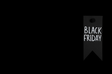 Photo of Tag with phrase Black Friday on dark background, space for text