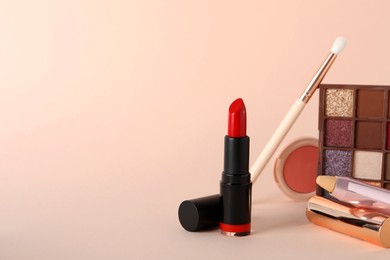 Beautiful red lipstick and cosmetic products on beige background, space for text