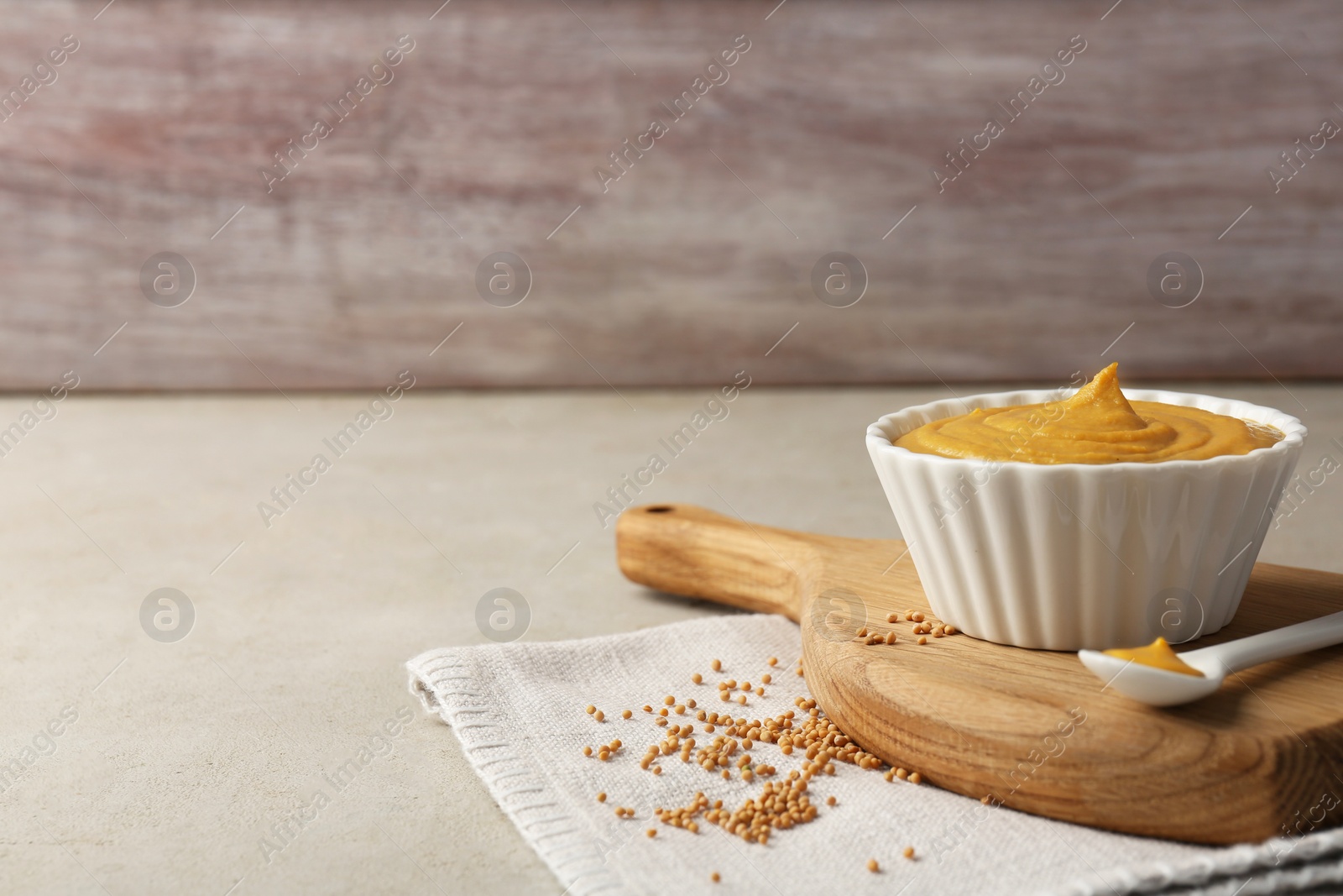 Photo of Tasty mustard sauce and dry seeds on light textured table, space for text