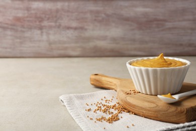 Photo of Tasty mustard sauce and dry seeds on light textured table, space for text