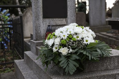 Funeral wreath of flowers on granite tombstone in cemetery