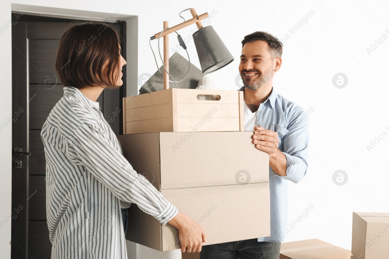 Photo of Happy couple with moving boxes entering in new apartment