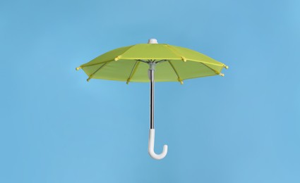 Photo of Open small yellow umbrella on light blue background