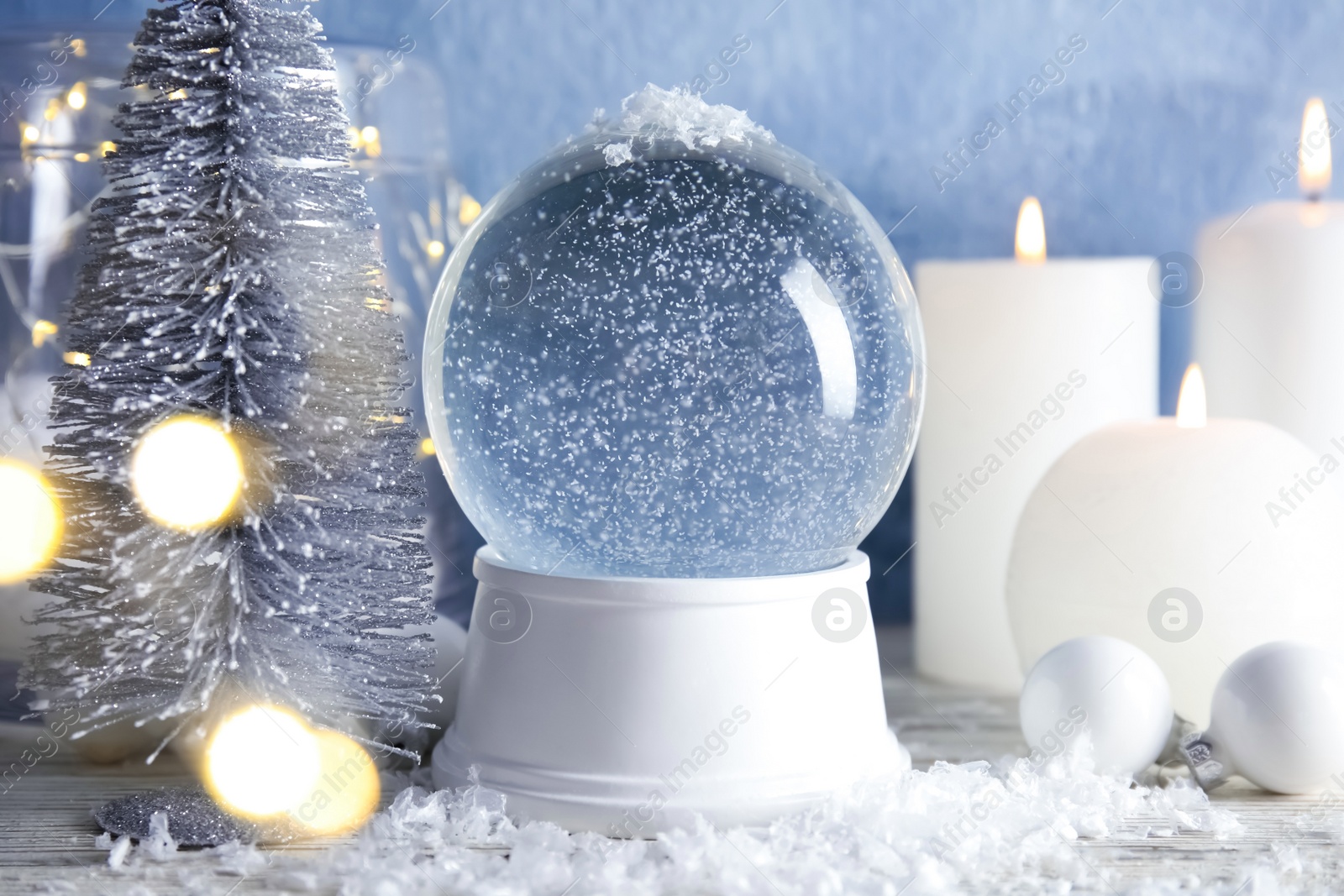 Photo of Magical empty snow globe with Christmas decorations and candles on table