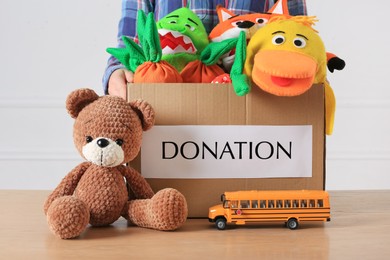 Photo of Little boy holding donation box with toys against white background, closeup
