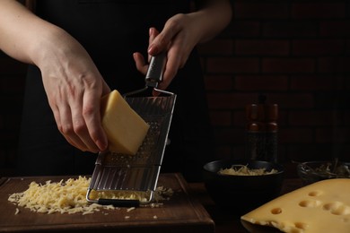 Photo of Woman grating cheese at wooden table, closeup