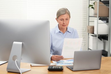 Photo of Senior accountant working at wooden desk in office