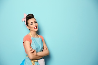 Portrait of funny young housewife on color background