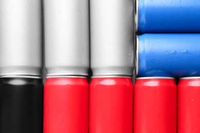 Energy drinks in wet cans as background, top view