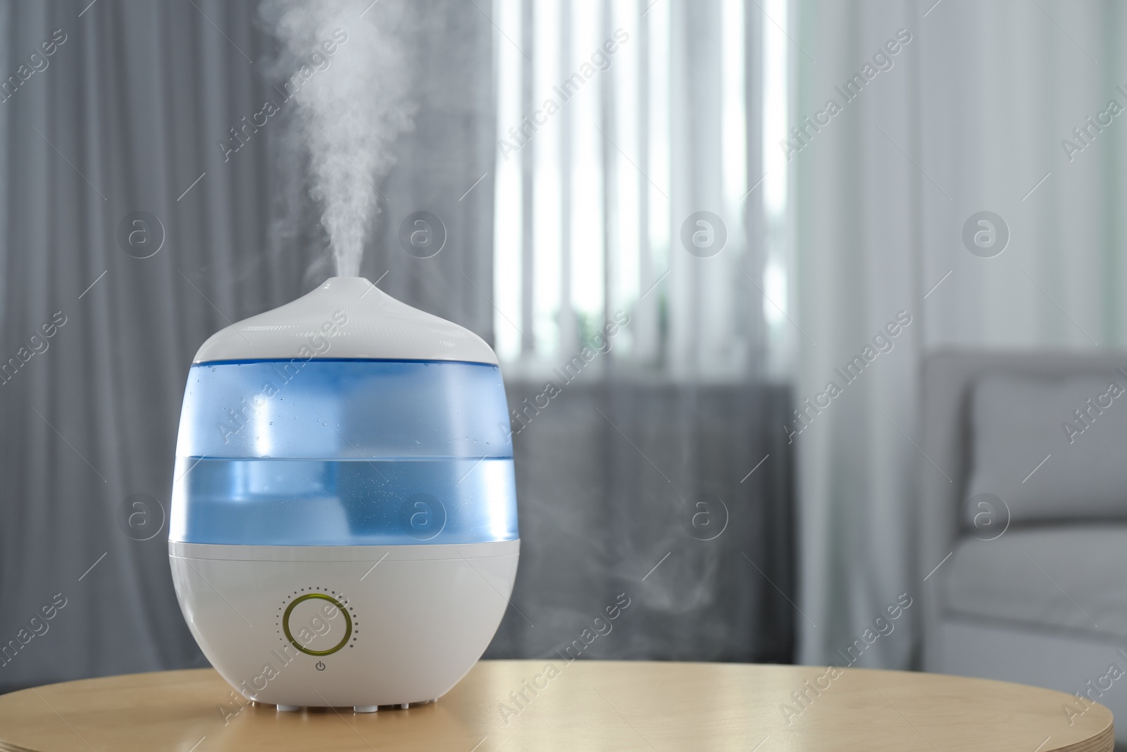 Photo of Modern air humidifier on table indoors. Space for text