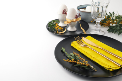 Festive Easter table setting with fresh mimosa flowers. Space for text