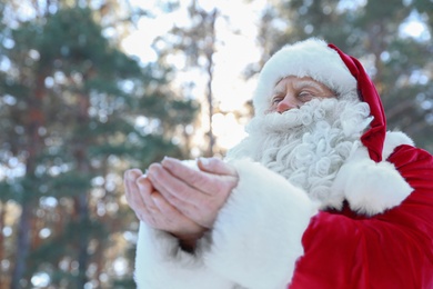 Photo of Happy Authentic Santa Claus with snow in his hands outdoors