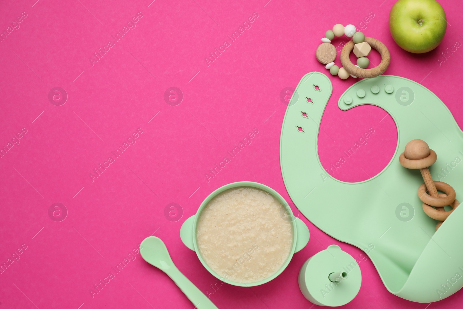 Photo of Silicone baby bib, toys and plastic dishware with healthy food on pink background, flat lay. Space for text