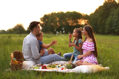 Photo of Happy family having picnic in park at sunset