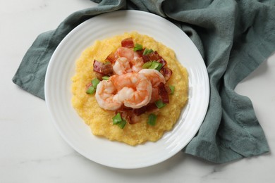 Photo of Plate with fresh tasty shrimps, bacon, grits and green onion on white marble table, top view