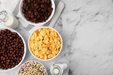 Photo of Different delicious breakfast cereals and milk on white marble table, flat lay. Space for text