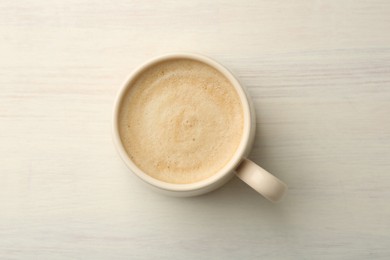 Cup of coffee on white wooden table, top view