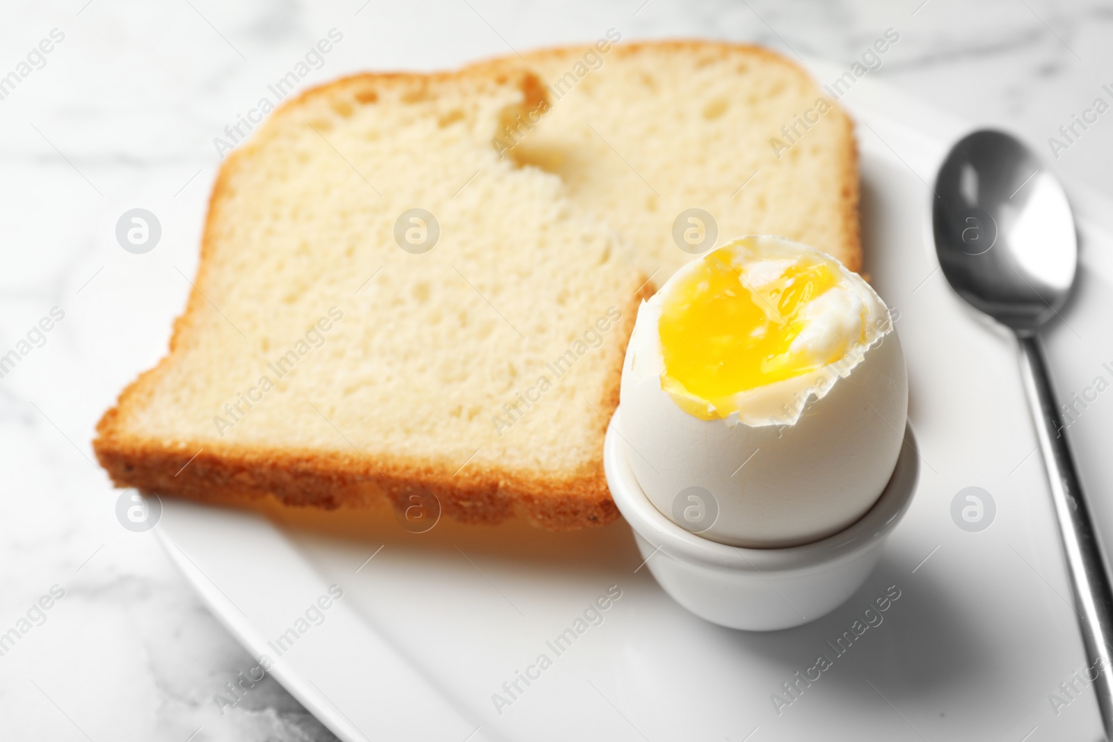 Photo of Holder with soft boiled egg and bread on plate. Space for text