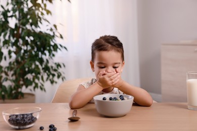 Photo of Cute little girl covering her mouth and refusing to eat breakfast at home