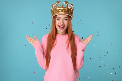 Photo of Beautiful young woman with inflatable crown under falling confetti on light blue background