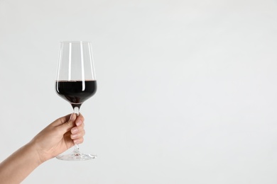 Photo of Woman holding glass of red wine on light background, closeup. Space for text