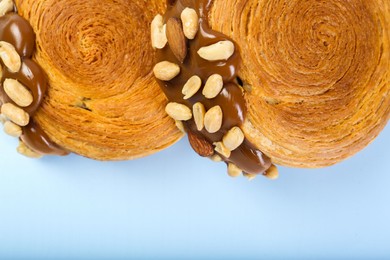 Tasty puff pastry. Supreme croissants with chocolate paste and nuts on light blue background, top view. Space for text