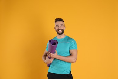 Photo of Handsome man with yoga mat on yellow background