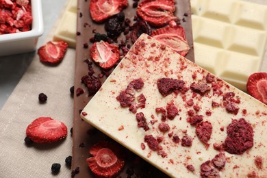 Photo of Different chocolate bars with freeze dried fruits on table, closeup