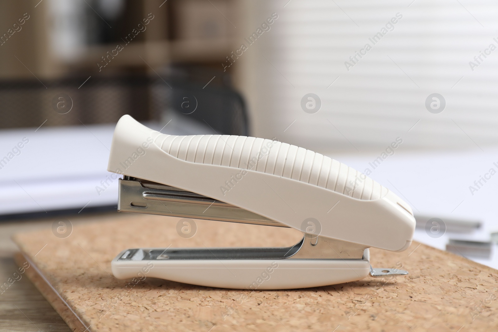 Photo of Stapler and notebook on table indoors, closeup