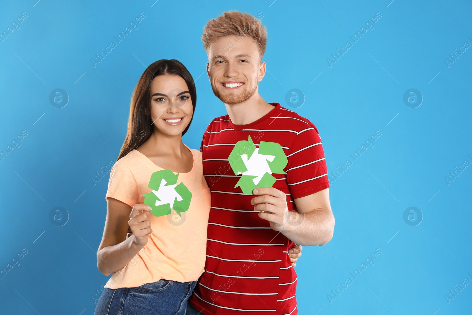 Photo of Young couple with recycling symbols on blue background