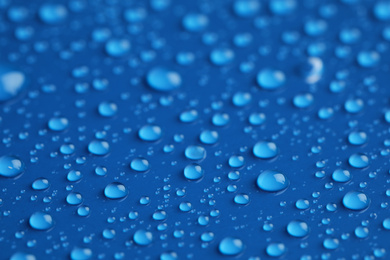 Photo of Water drops on blue background, closeup view