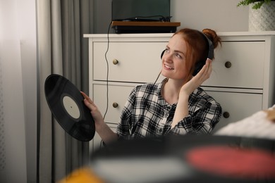 Young woman listening to music with turntable at home