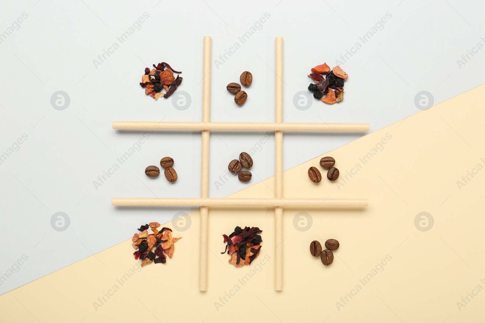 Photo of Tic tac toe game made with coffee beans and dry tea leaves on color background, top view