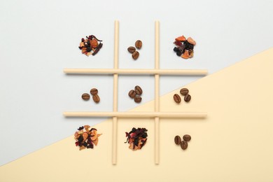 Tic tac toe game made with coffee beans and dry tea leaves on color background, top view