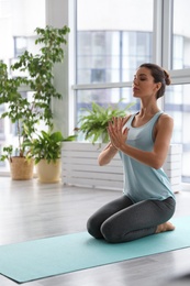 Young woman practicing thunderbolt asana in yoga studio. Vajrasana pose