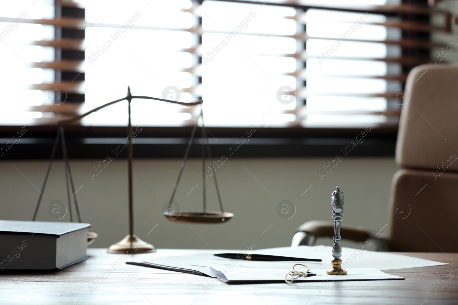 Photo of Stamp, documents and scales of justice on wooden table in notary's office. Space for text