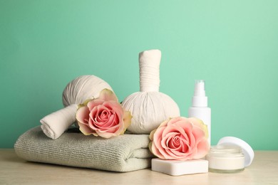 Photo of Composition with different spa products and roses on beige table against turquoise background