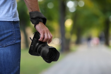 Photographer with professional camera in park, closeup