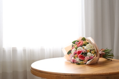 Photo of Beautiful flower bouquet on table near window in room. Space for text