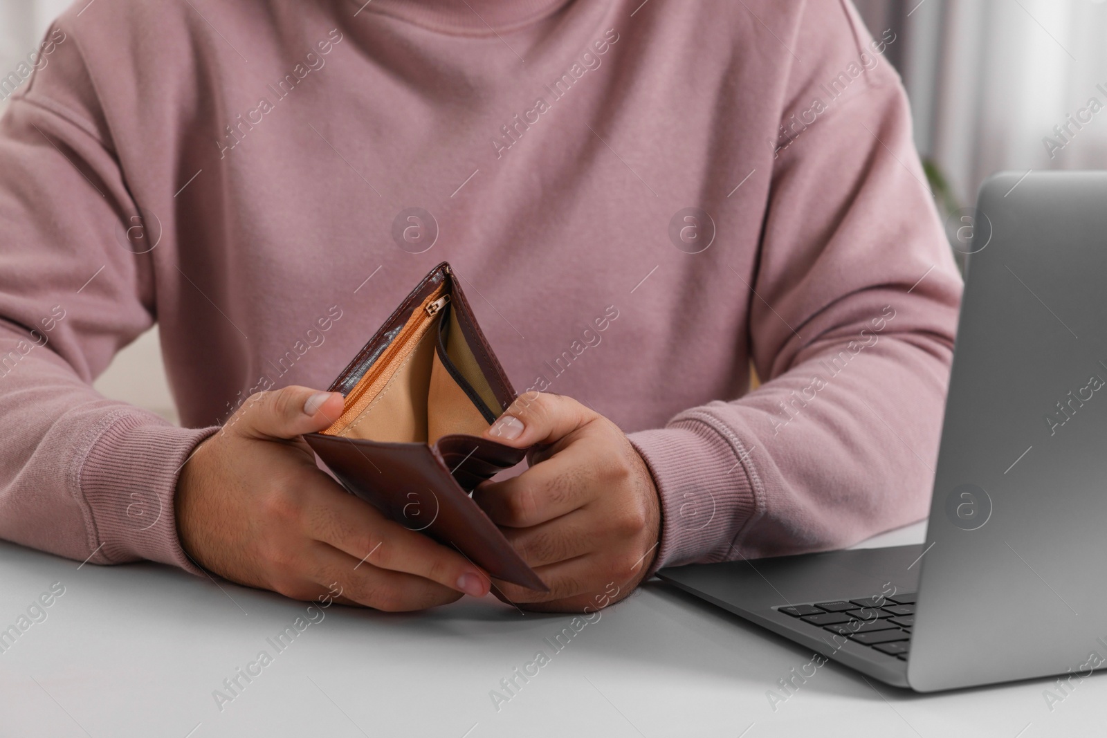 Photo of Man with empty wallet at white table indoors, closeup