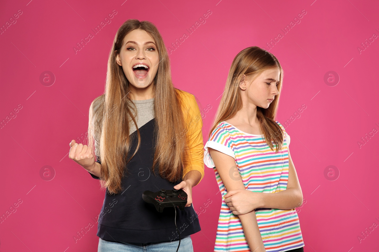 Photo of Young woman and teenage girl playing video games with controllers on color background