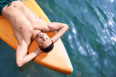 Photo of Man lying on SUP board in sea, top view. Space for text